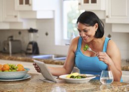 Mujer con sobrepeso que come sano mientras mira las redes sociales en la tableta