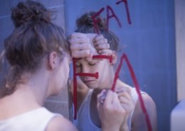 Chica en el baño escribiendo grasa en la ventana