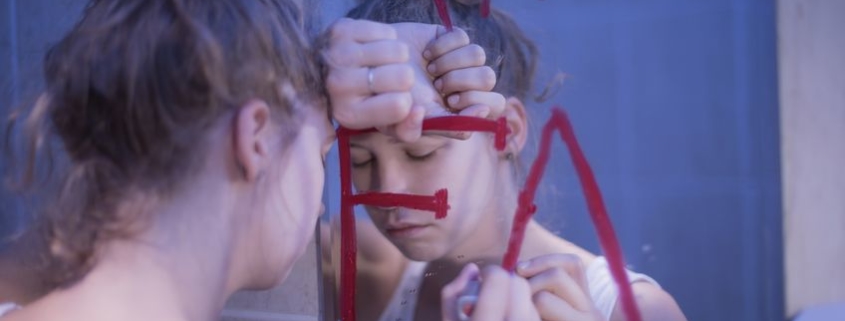 Girl in bathroom writing fat in window