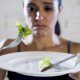 woman eating lettuce on white plate