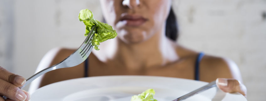 woman eating lettuce on white plate