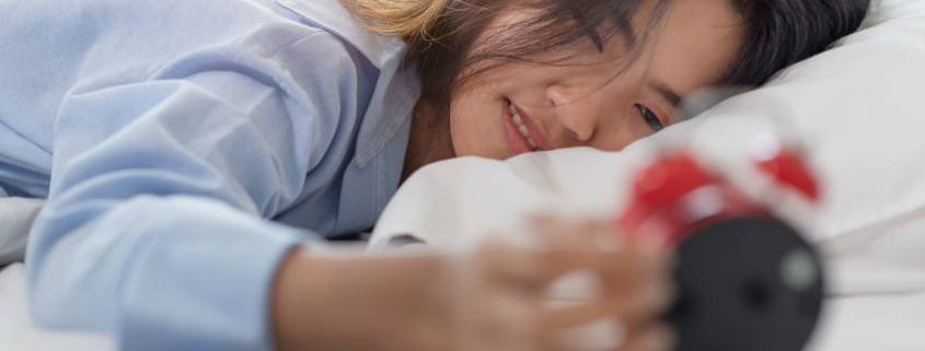 woman looking at alarm clock in morning