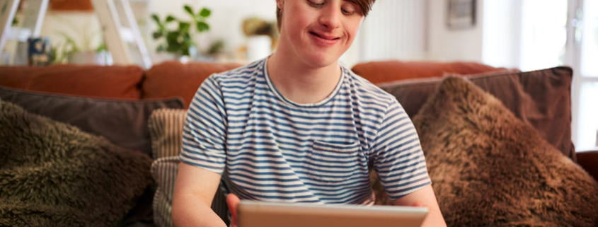 Young down syndrome man using mental health apps at home