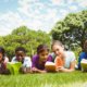 Children reading books on grass at park