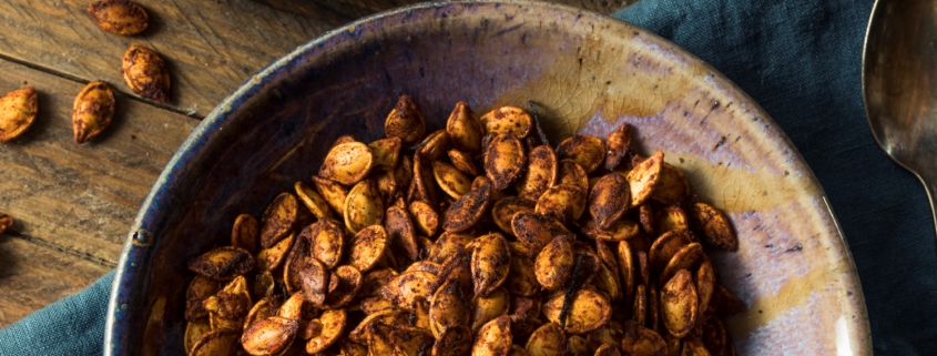 Spicy roasted pumpkin seeds in bowl on table