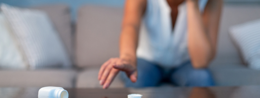 Woman on couch crying with pills on table