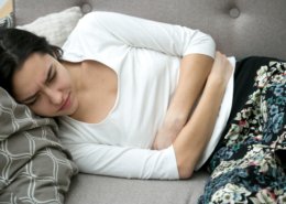 mujer con dolor de estómago descansando en el sofá
